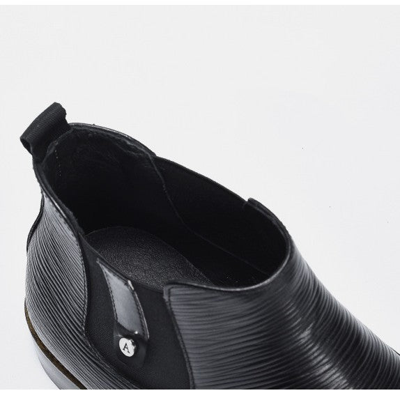 Black leather ankle boot with a glossy finish on a light gray background