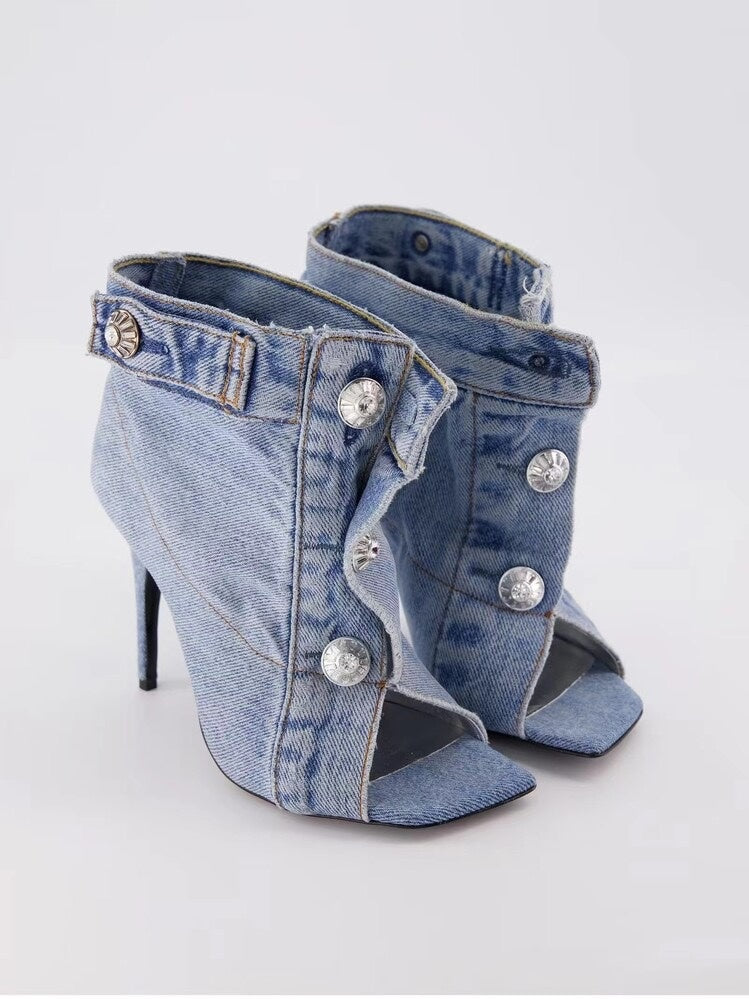 Denim high-heeled shoes with embellishments on a light gray background