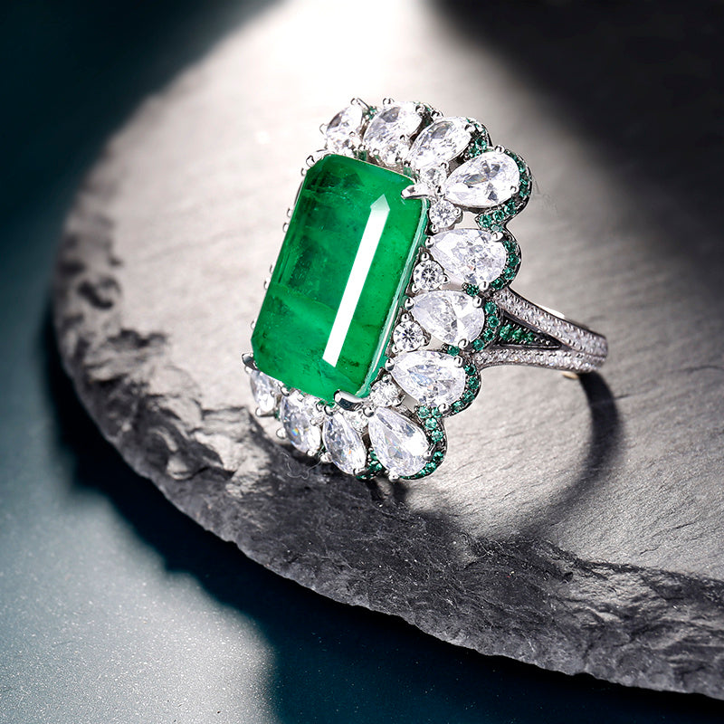 Emerald ring with diamonds on a stone surface