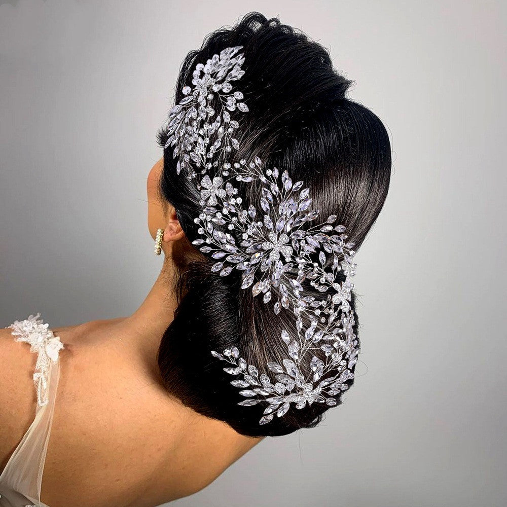 Woman with intricate hairpiece featuring silver flowers and beads on a plain background