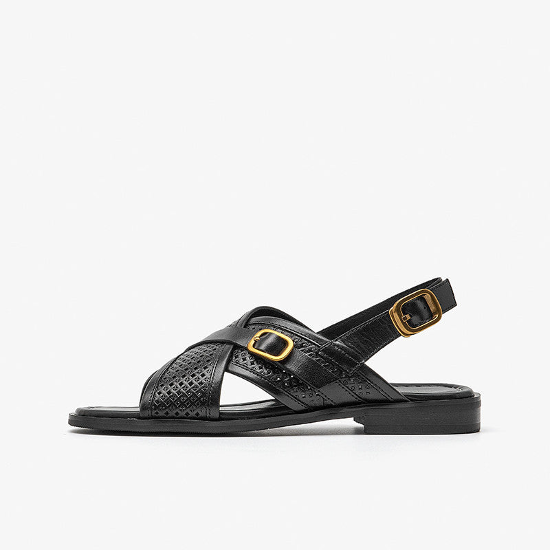 Black sandal with gold buckle on a white background