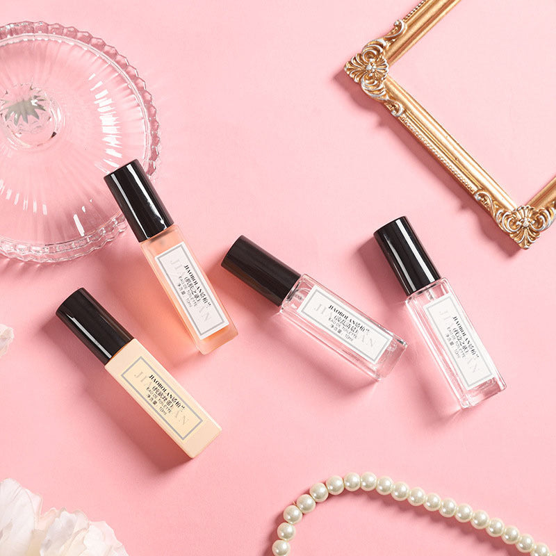 Four small bottles with black caps on a pink background