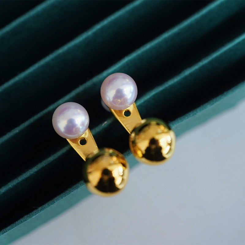 Pair of pearl and gold earrings on a green and gray striped background