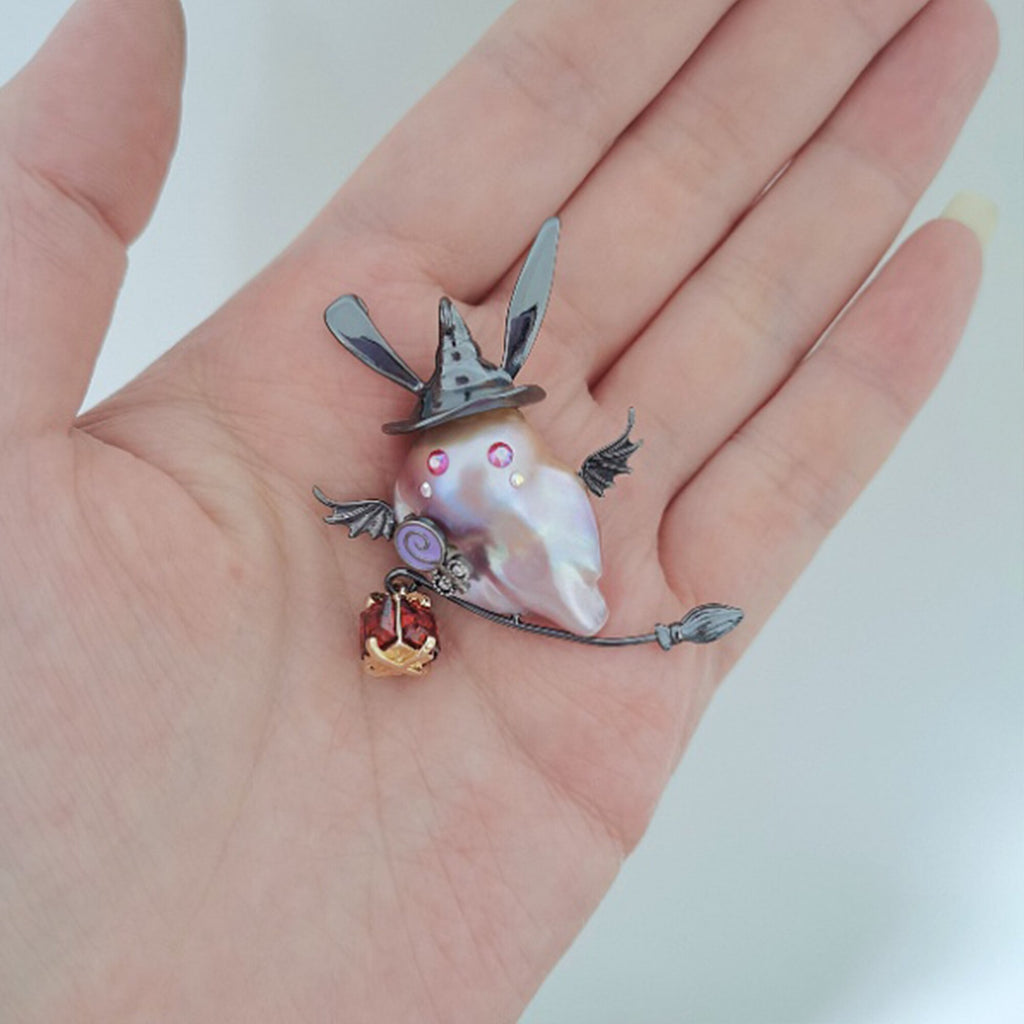 Decorative brooch with a shell-like center held in a hand against a white background