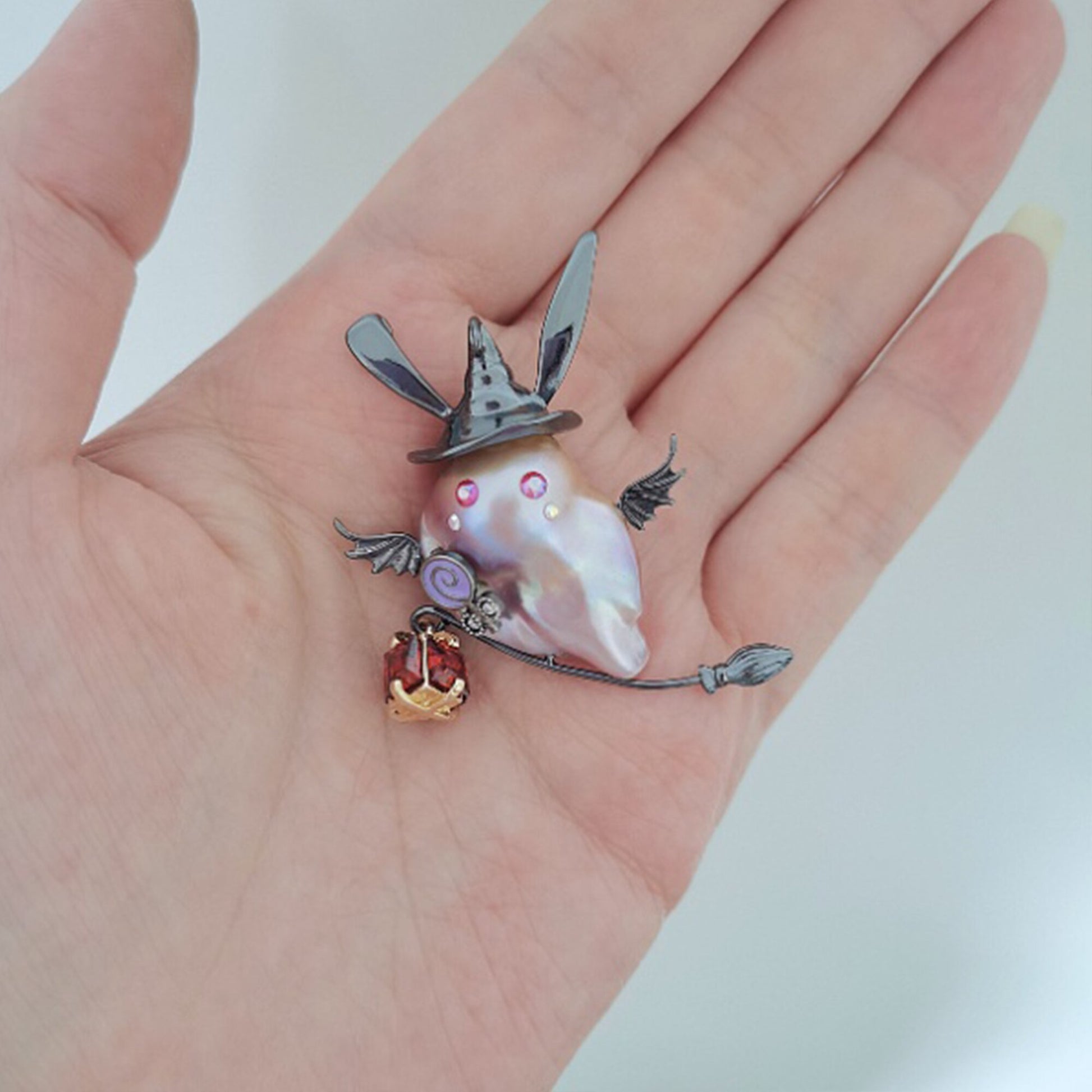 Decorative brooch with a shell-like center held in a hand against a white background