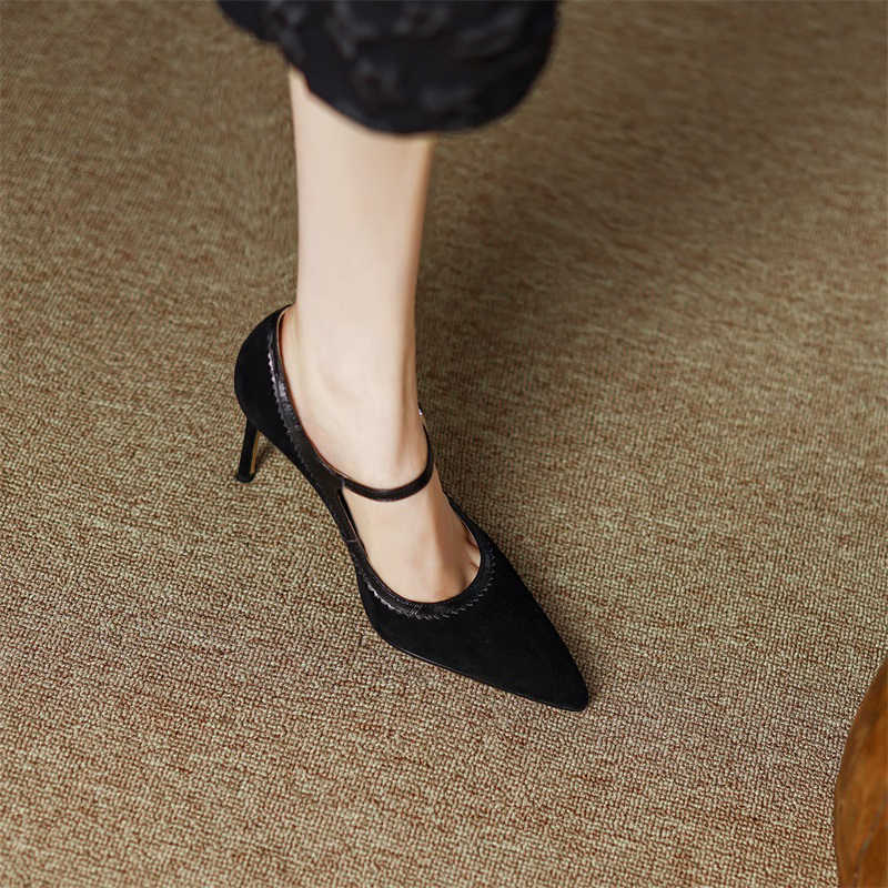 Black high-heeled shoes worn on a textured brown floor