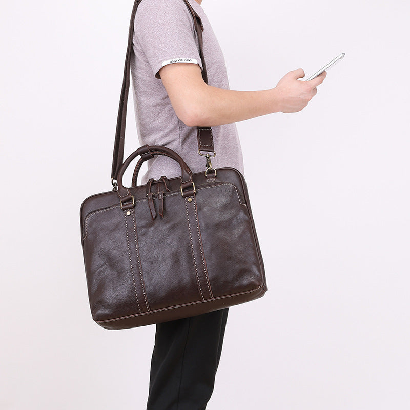 Person holding a brown leather briefcase and a smartphone on a white background