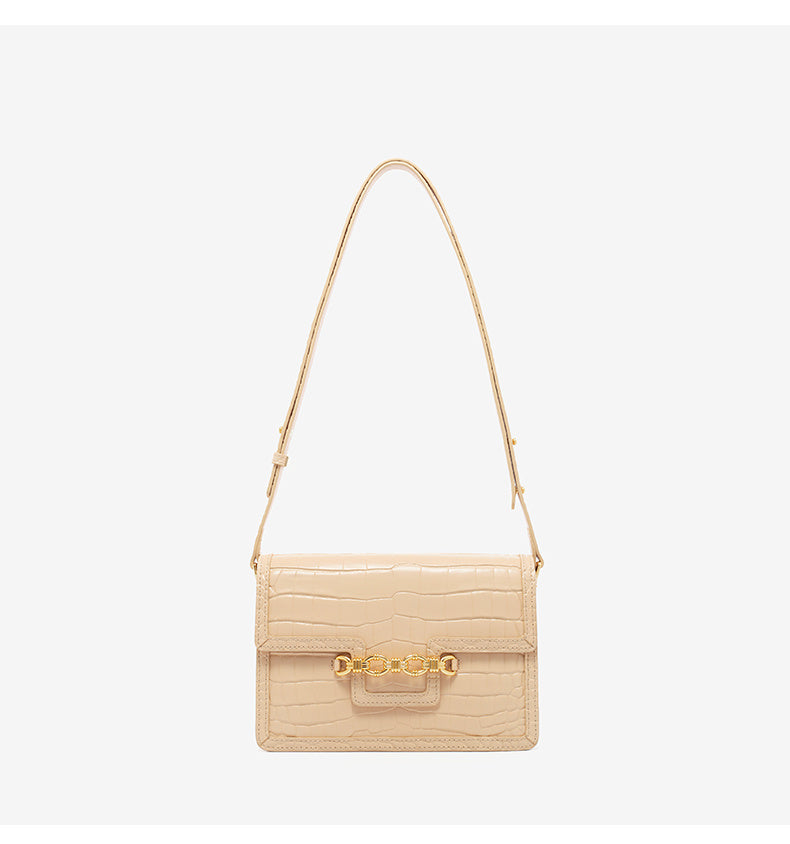 Beige handbag with gold accents on a light gray background