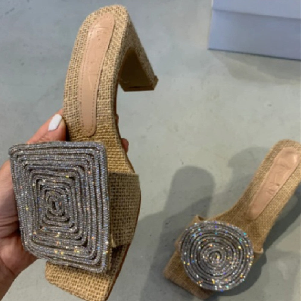 Gold high-heeled shoes with rhinestone embellishments on a gray surface