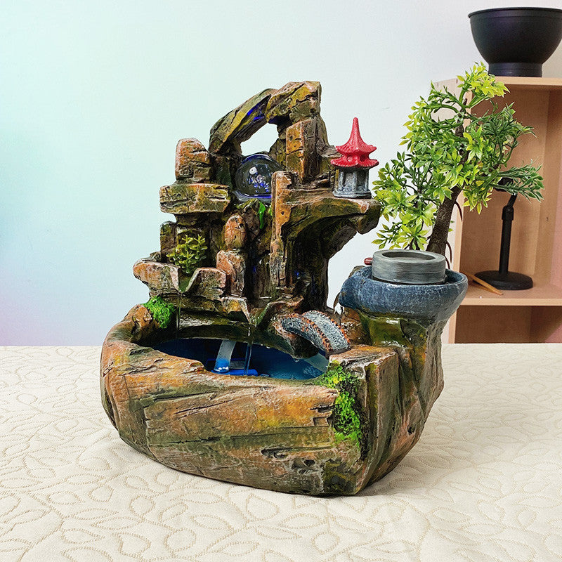 Decorative water fountain with rock structure and small lamp on a white surface.