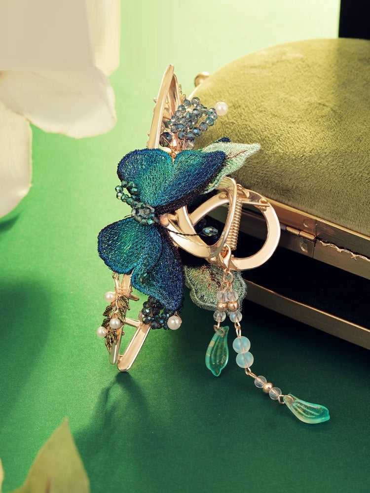 Decorative brooch with blue and green leaves on a green background