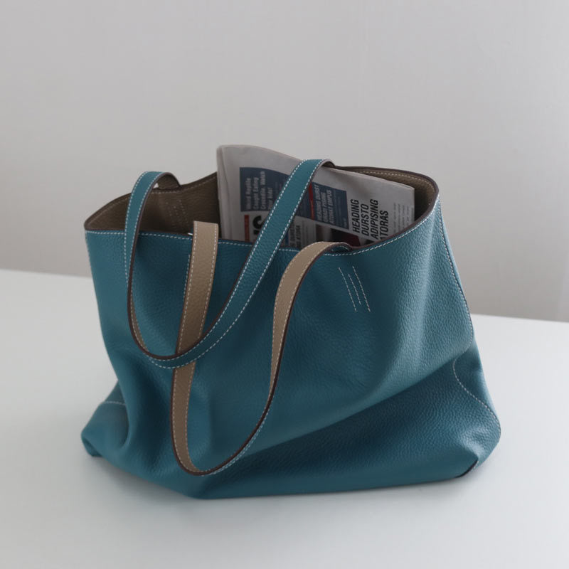 Blue tote bag with brown handles on a white surface