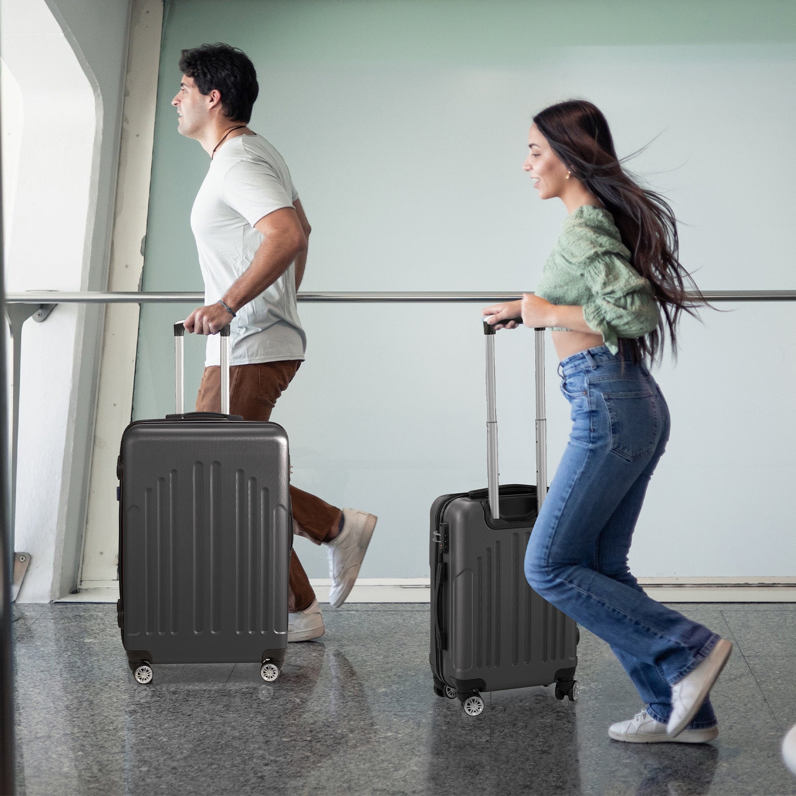 Two people with black suitcases walking in an airport.