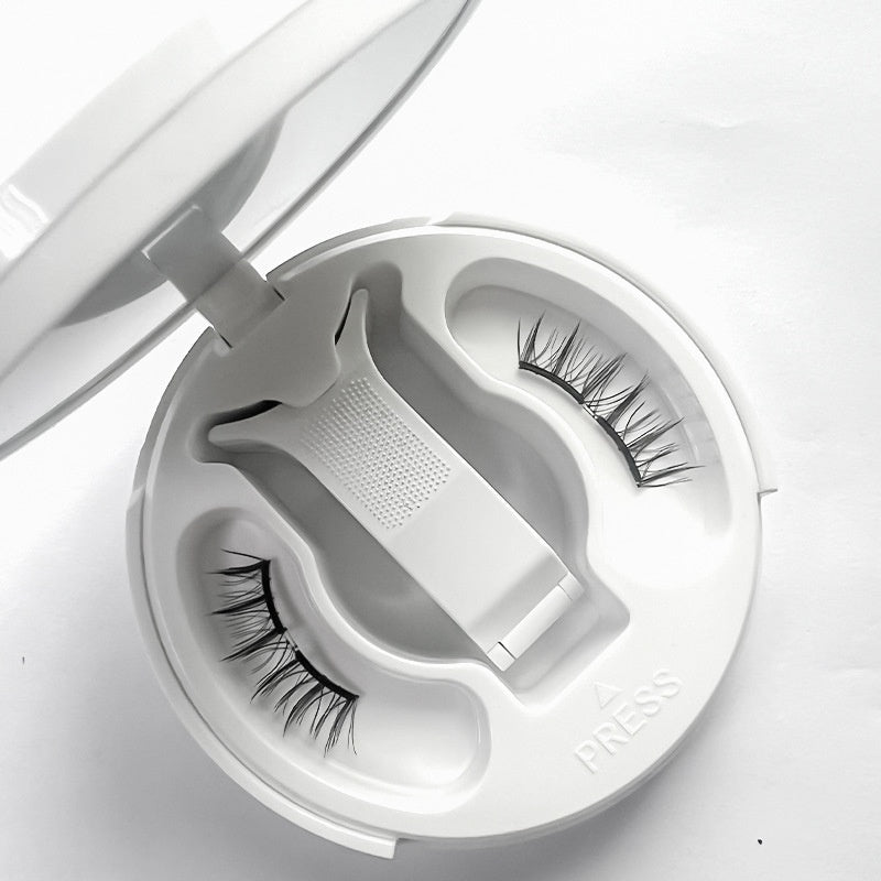 False eyelashes in a white container with a applicator on a light gray background