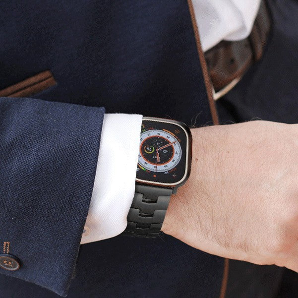 Person wearing a smartwatch with a black metal band on a blurred background