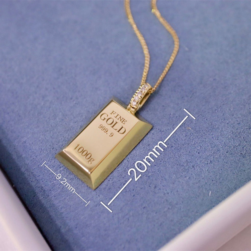 Gold bar pendant necklace with measurements on a blue background