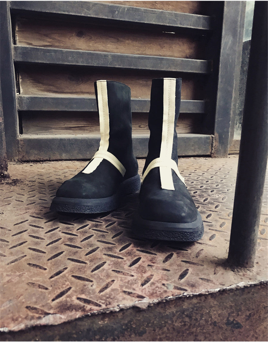 Pair of black boots with white straps on a metal surface