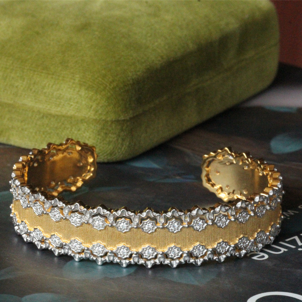 Gold bracelet with diamond accents on a green fabric background