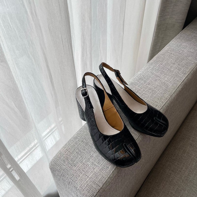 Black shoes on a gray surface with white curtains in the background