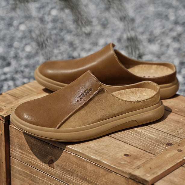 Pair of brown slip-on shoes on a wooden surface with a blurred natural background