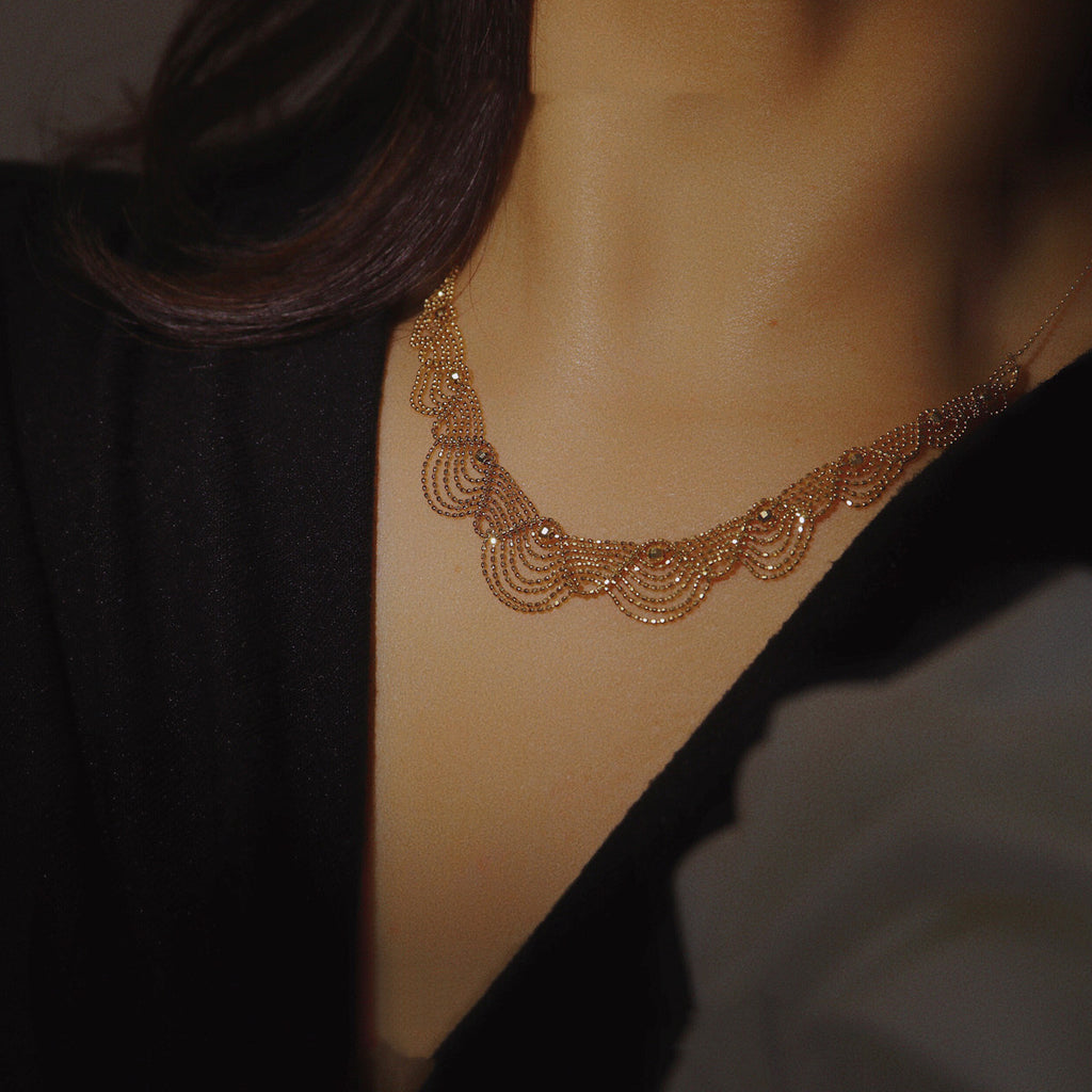 Close-up of a person wearing a gold necklace with a dark background