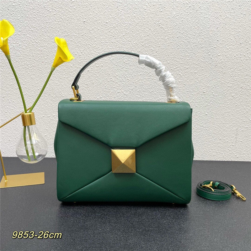 Green handbag with gold accent on a dark surface with a light gray background