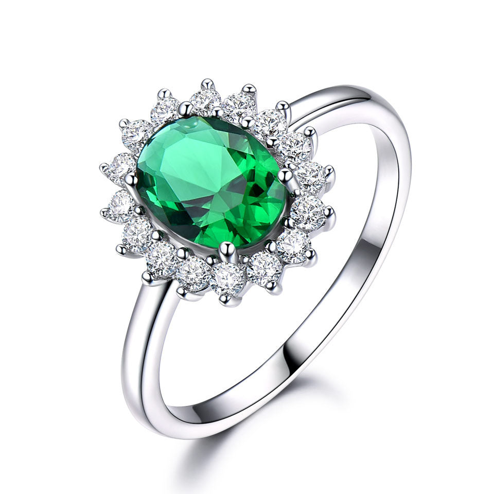 Silver ring with a green gemstone and diamond accents on a white background