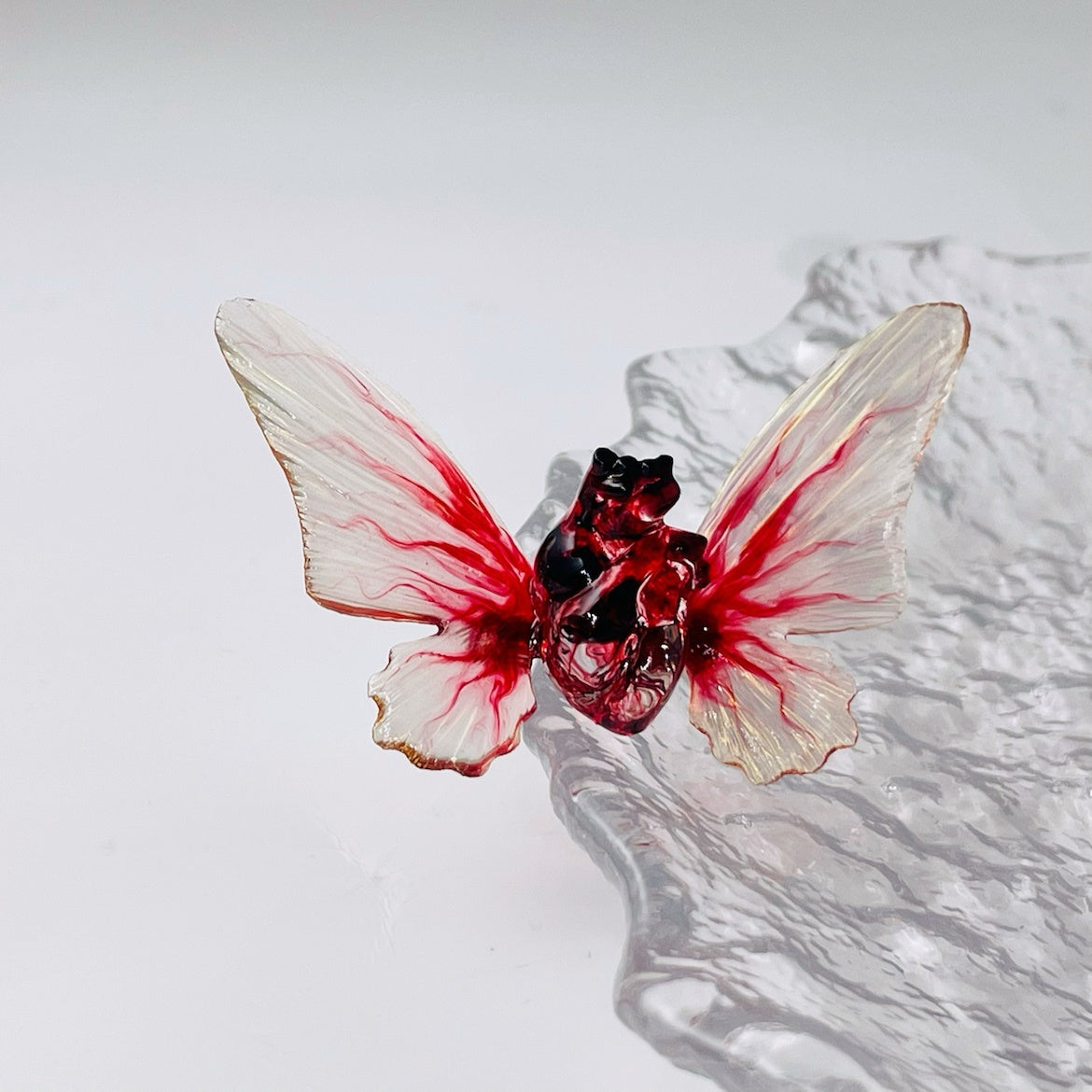 Butterfly-shaped object with red and white wings on a textured surface