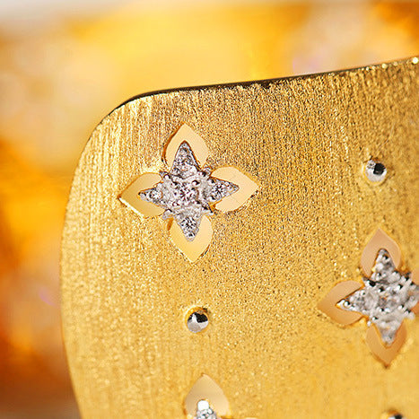 Gold earrings with star designs on a gold surface