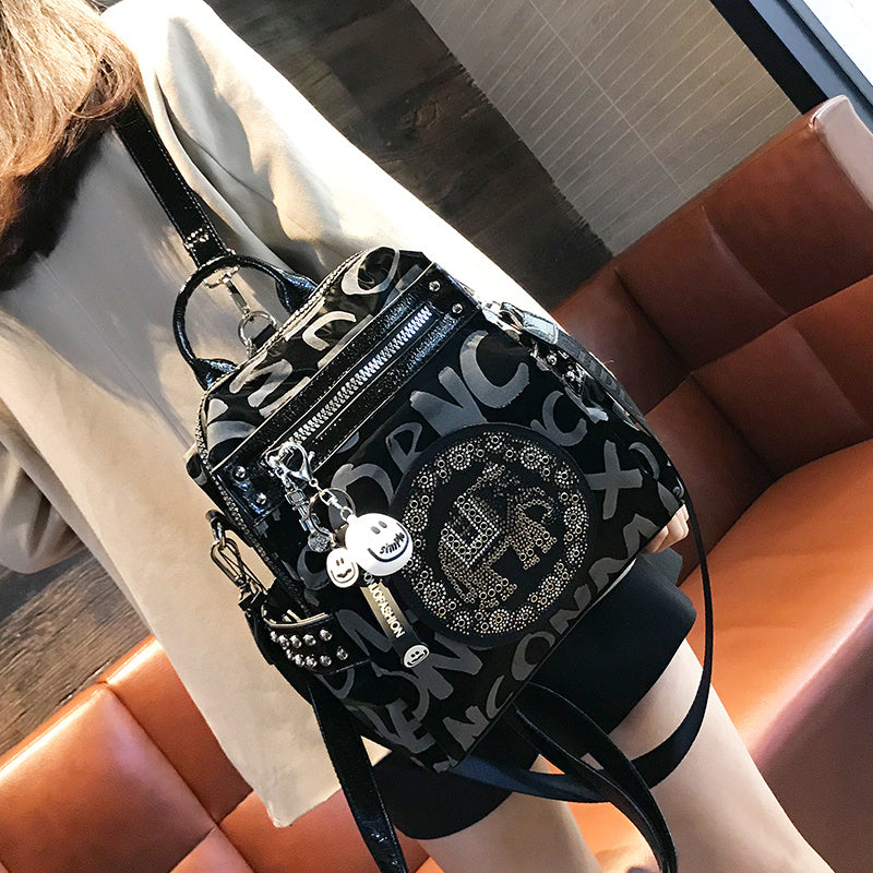 Black backpack with decorative elements on a person sitting on an orange couch.