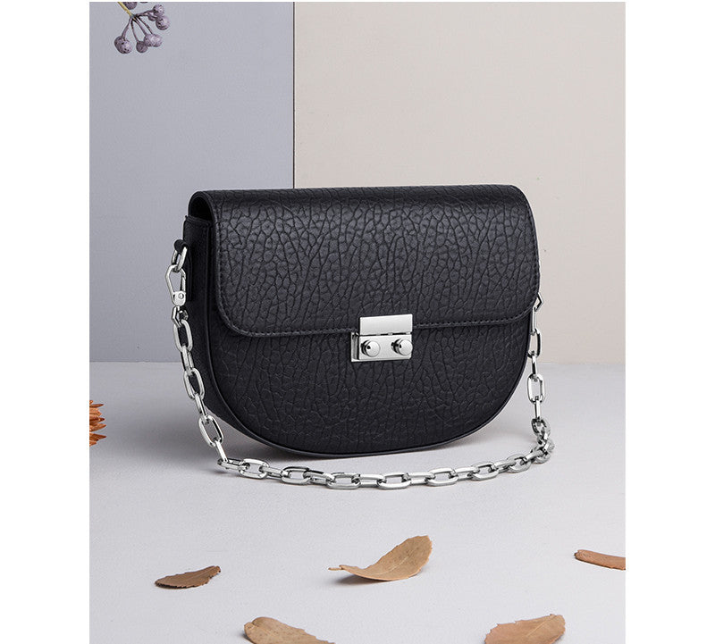 Black textured handbag with a chain strap on a light gray background