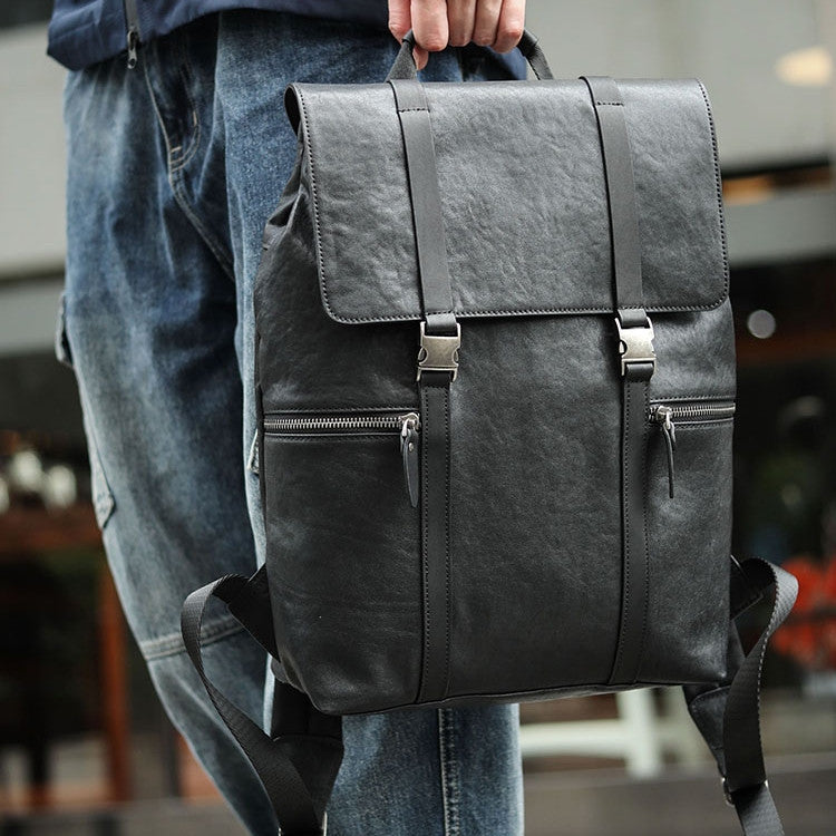 Person holding a dark gray backpack with a blurred background