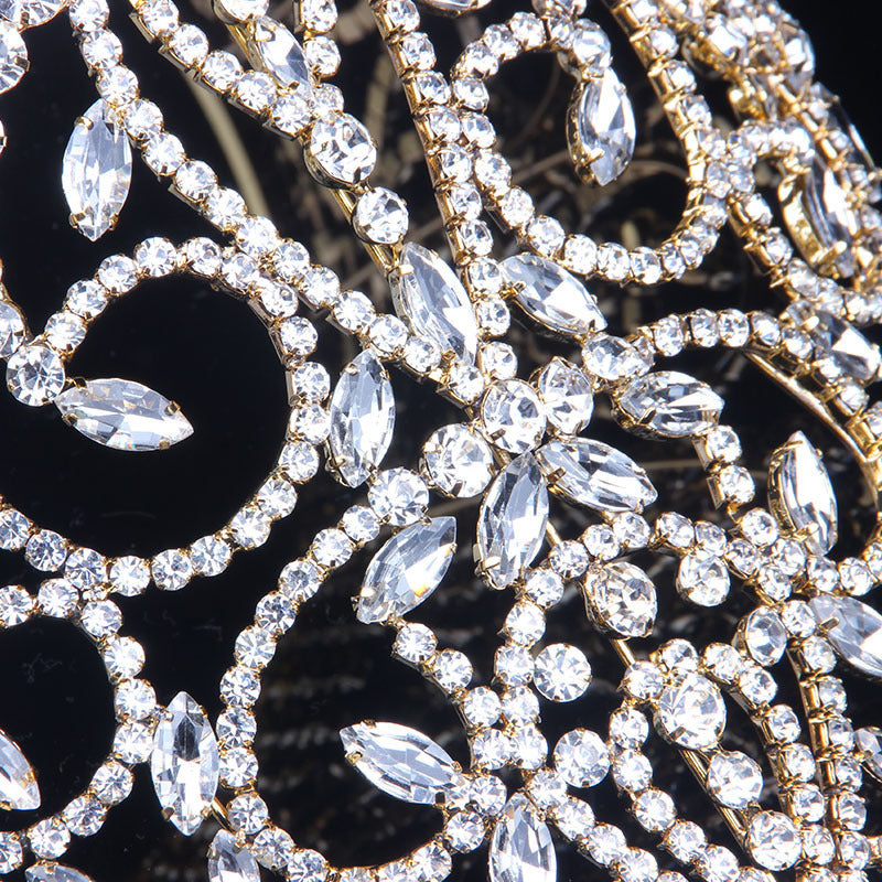 Close-up of a decorative headband with crystals and gold accents on a black background