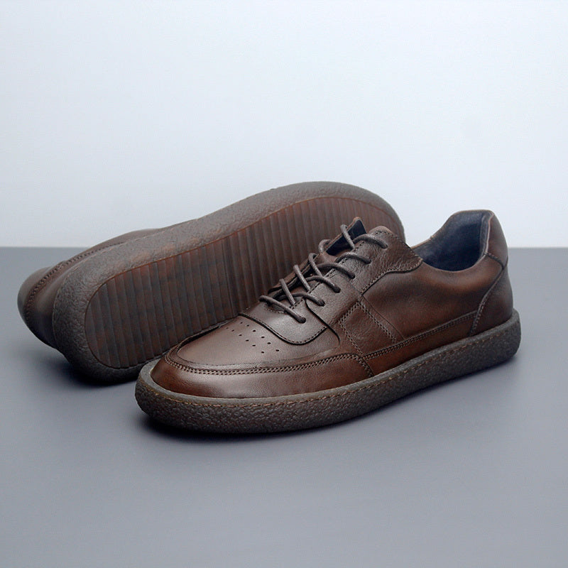 Pair of brown leather shoes on a gray surface with a light gray background