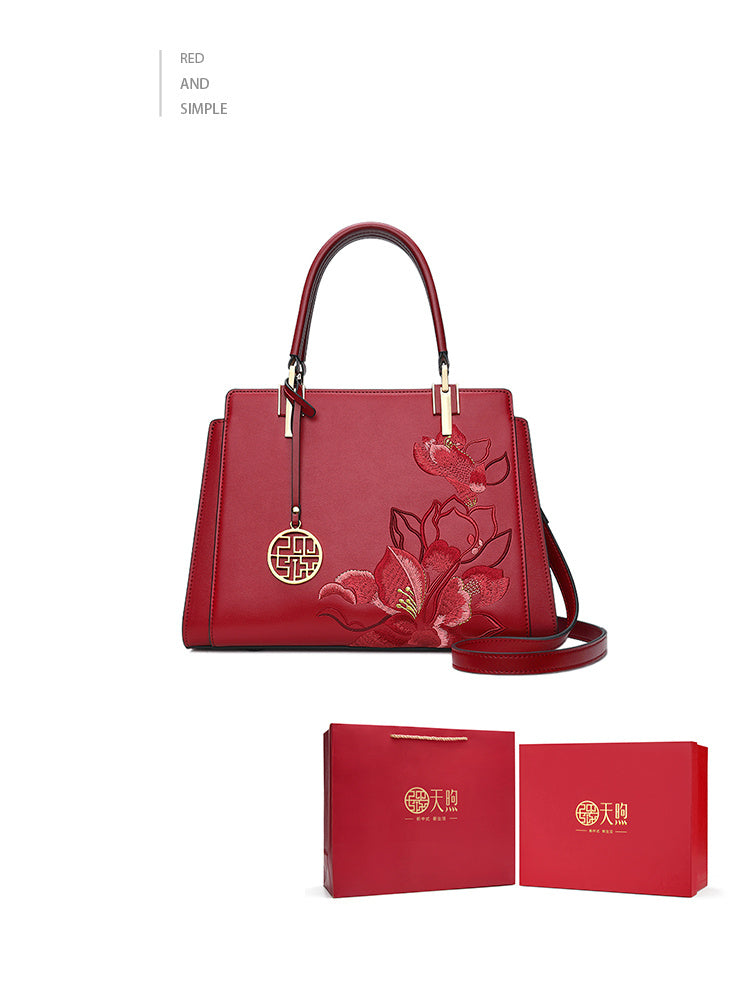 Red handbag with floral design and matching box on a white background