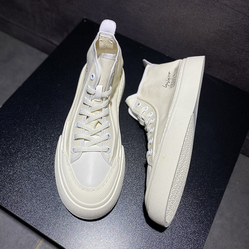 Pair of beige high-top sneakers on a dark surface