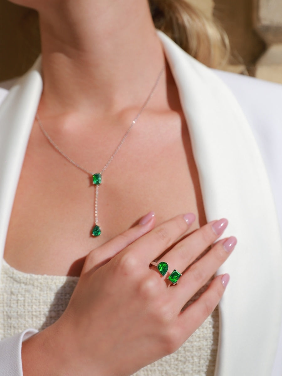 Green gemstone necklace and earrings on a person wearing a white outfit.