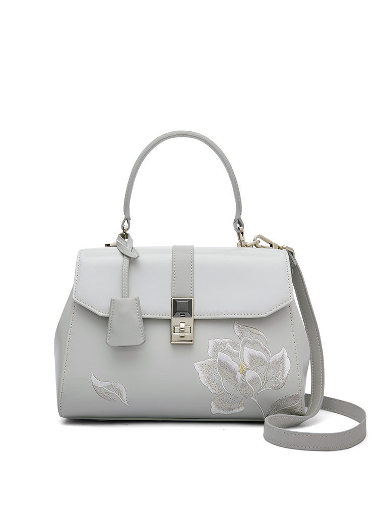 Light gray handbag with floral embroidery on a white background