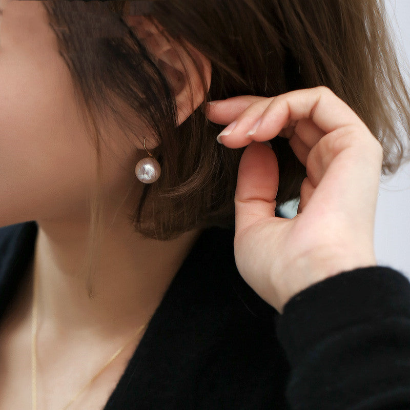Person wearing a pearl earring with a blurred background