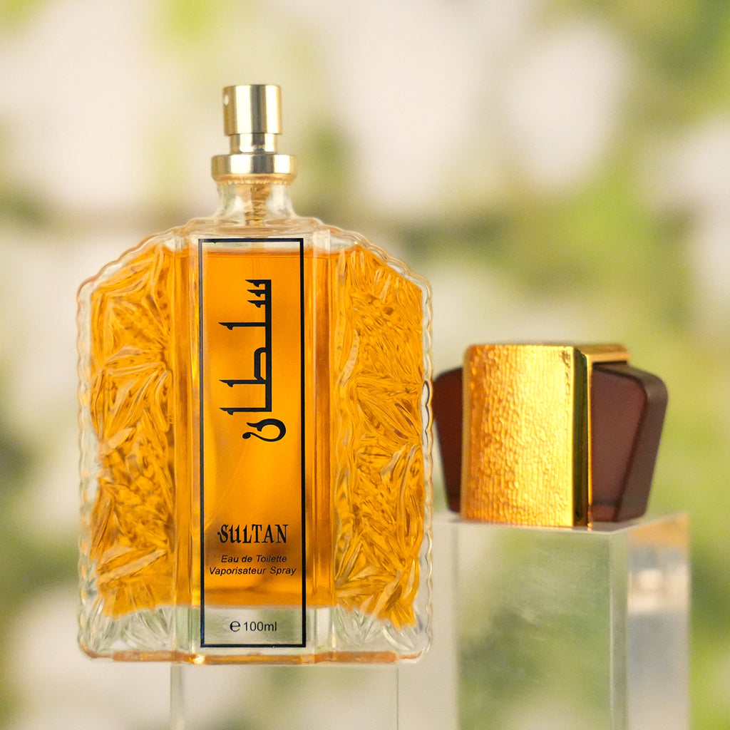 Perfume bottle with gold cap and detailed label against a blurred natural background