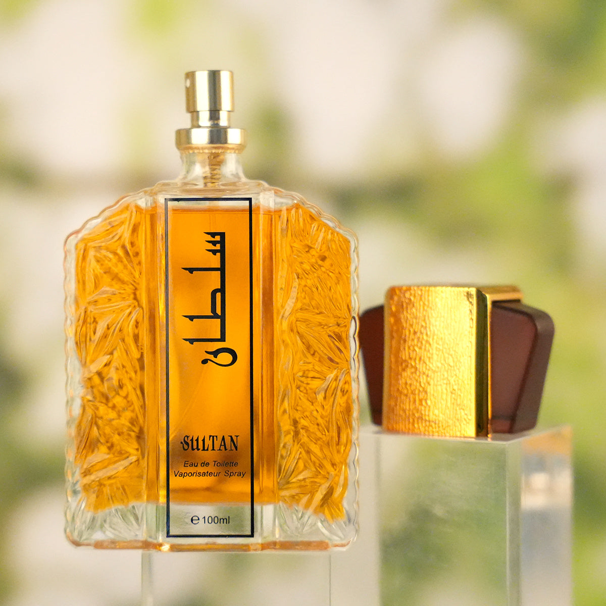 Perfume bottle with gold cap and detailed label against a blurred natural background