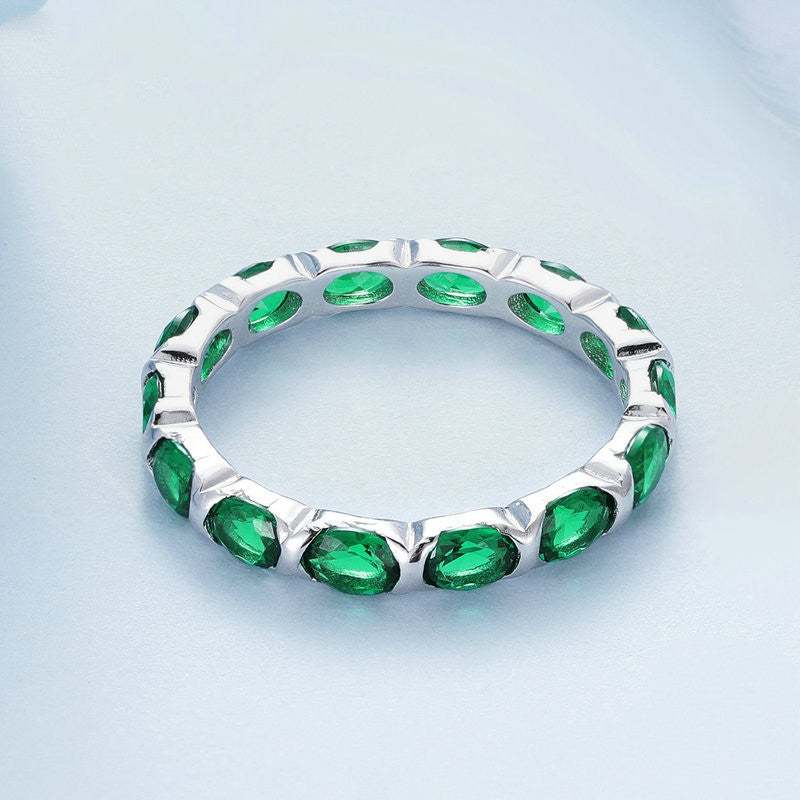 Silver ring with green gemstones on a light blue background