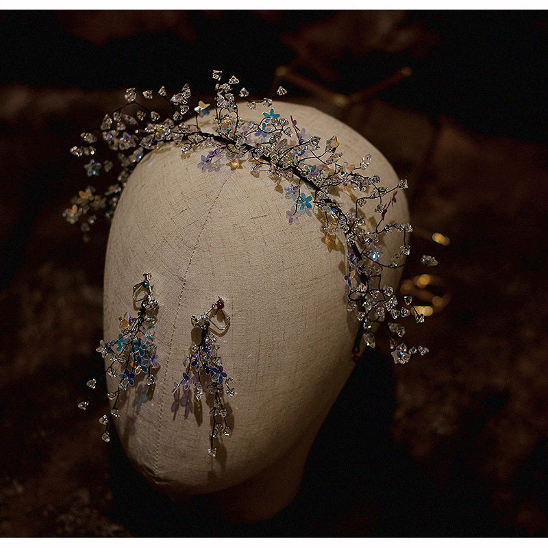 Decorative headpiece and earrings on a mannequin head against a dark background