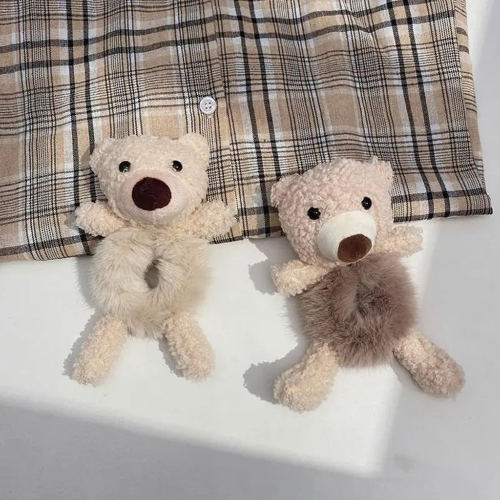 Two teddy bears on a white surface with a plaid fabric background