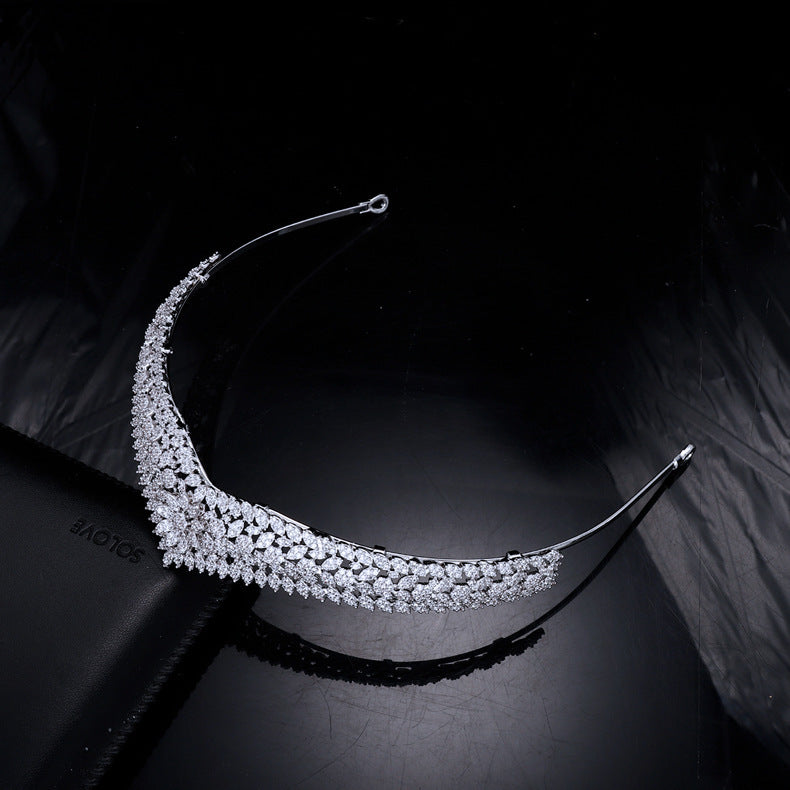 Silver tiara on a black surface with a dark background
