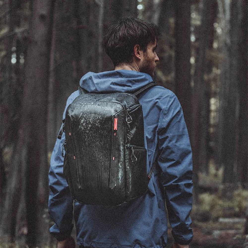 Person wearing a black backpack and blue jacket walking through a forest
