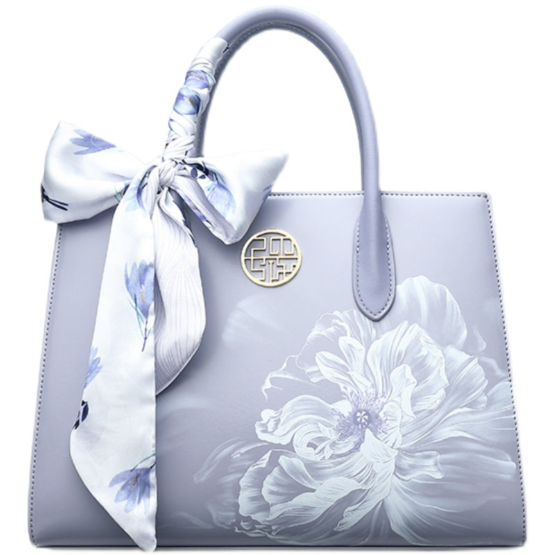 Light blue handbag with floral design and matching scarf on a white background
