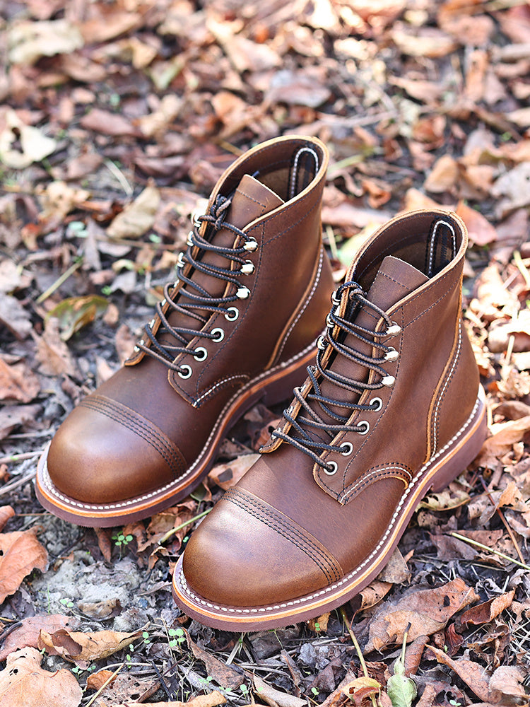 Pair of brown leather boots on a ground covered with leaves
