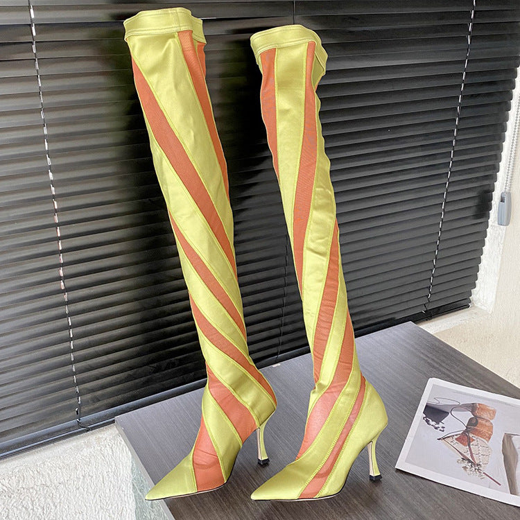 Yellow and orange striped knee-high boots on a wooden floor with a magazine in the background.