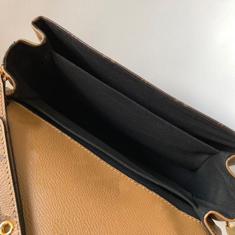 Close-up of a brown leather clutch with a black interior on a light gray background